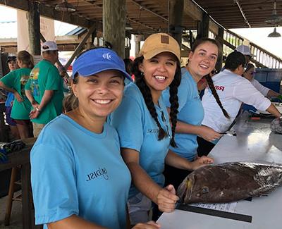 Marine sciences students working on a fish outside at dock.