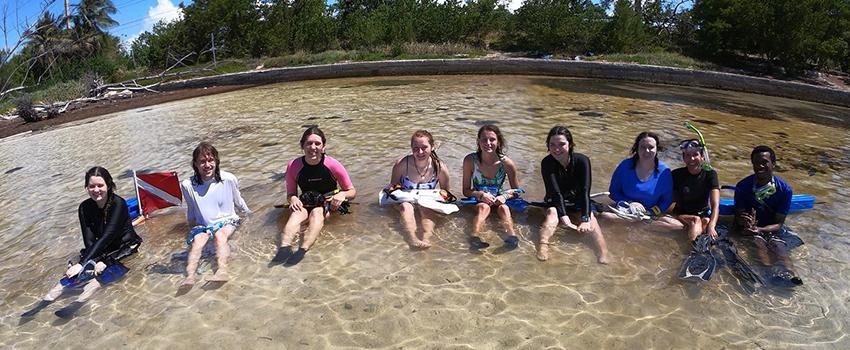 Marine Sciences students sitting in the water during class.